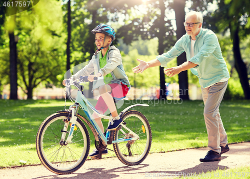 Image of grandfather and boy with bicycle at summer park