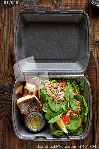 Image of fried salmon pieces and spinach salad in plastic box