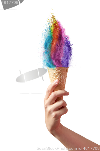 Image of Ice cream from rainbow dust splash in a waffle cone in a hand.