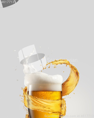 Image of Refreshing beer glass with splash and thick foam.