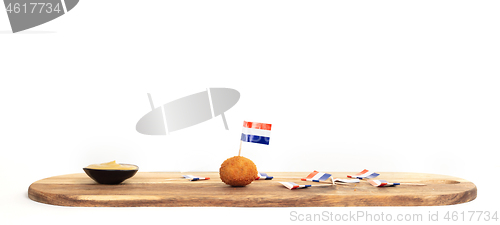 Image of Dutch traditional snack bitterbal, just one left on a wooden ser