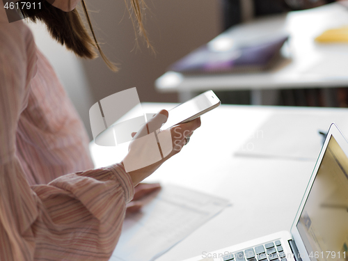 Image of Businesswoman typing on phone  in office