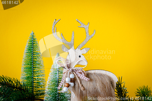 Image of Christmas decoration wooden reindeer with fir trees on yellow ba