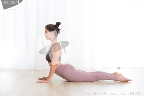 Image of Portrait of gorgeous active sporty young woman practicing yoga in studio. Beautiful girl practice Sasangasana, rabbit yoga pose. Healthy active lifestyle, working out indoors in gym