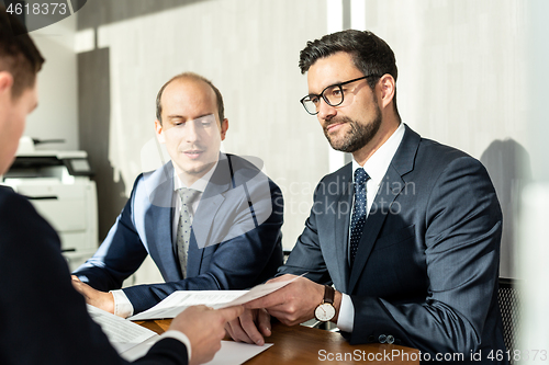 Image of Group of confident successful business people reviewing and signing a contract to seal the deal at business meeting in modern corporate office.