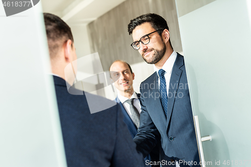 Image of Group of confident business people greeting with a handshake at business meeting in modern office or closing the deal agreement by shaking hands.