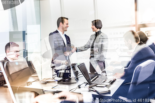 Image of Confident business people shaking hands in moder corporate office.