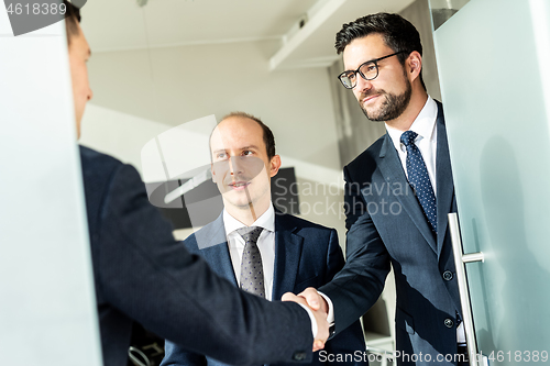 Image of Group of confident business people greeting with a handshake at business meeting in modern office or closing the deal agreement by shaking hands.