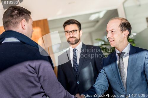 Image of Group of confident business people greeting with a handshake at business meeting in modern office or closing the deal agreement by shaking hands.