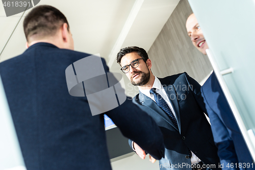 Image of Group of confident business people greeting with a handshake at business meeting in modern office or closing the deal agreement by shaking hands.