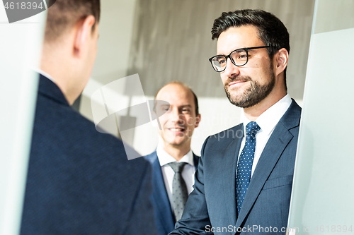 Image of Group of confident business people greeting with a handshake at business meeting in modern office or closing the deal agreement by shaking hands.