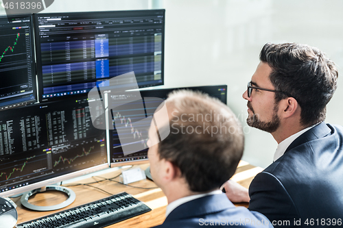 Image of Stock brokers looking at computer screens, trading online.