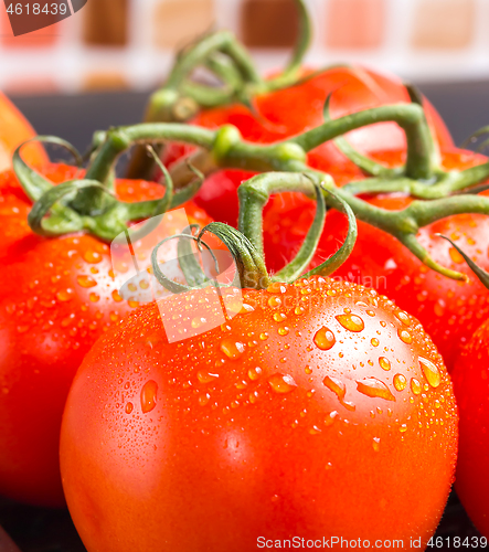 Image of Bunch of red juicy tomatoes with water droplets in kitchen 