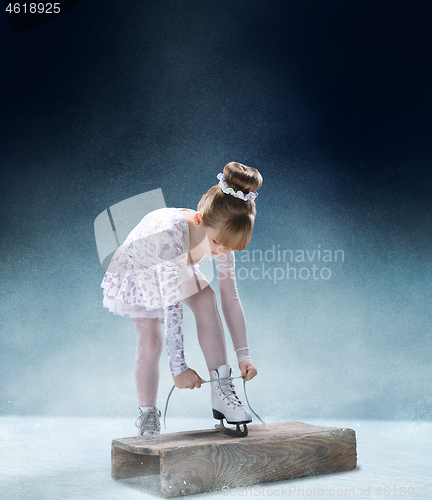 Image of Little girl figure laces up his shoes indoor ice arena.