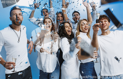 Image of Group of cheerful joyful young people standing and celebrating together over blue background