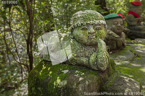 Image of Snake - symbol of japanese horoscope. Childish Jizo stone statue wearing knitted and cloth hats with zodiac animal.