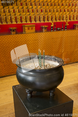 Image of Burner pot with burning black incense sticks in japanese temple.