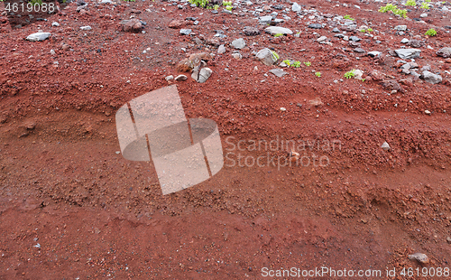 Image of A cut of soil with rocks and red soil