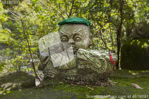 Image of Dragon - symbol of japanese horoscope. Childish Jizo stone statue wearing knitted and cloth hats with zodiac animal.