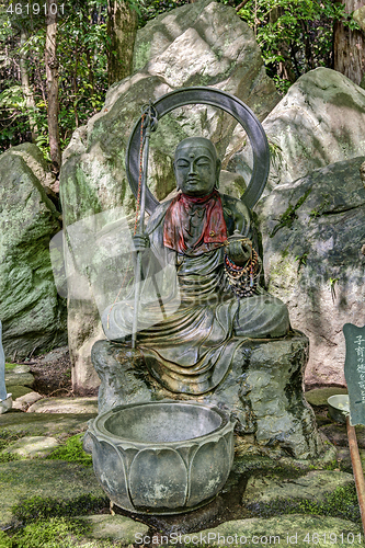 Image of statue of buddha in natural garden on rocky background