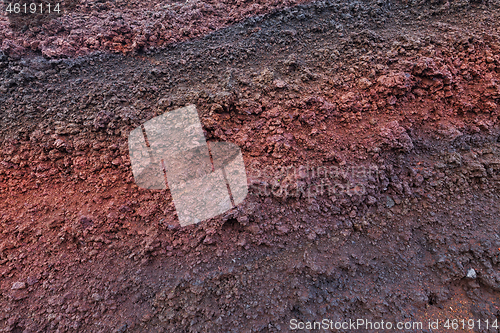 Image of A cut of soil with rocks and red soil