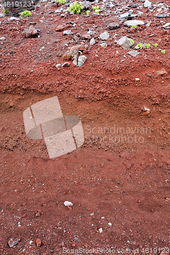 Image of A cut of soil with rocks and red soil