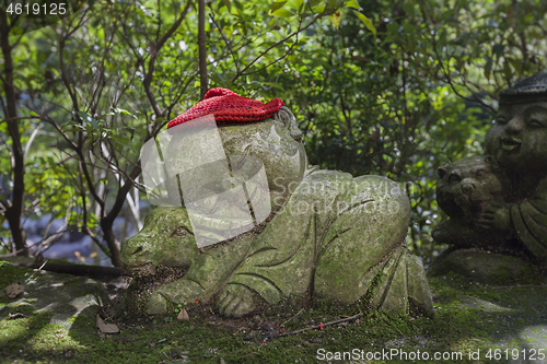 Image of Bull - symbol of japanese horoscope. Childish Jizo stone statue wearing knitted and cloth hats with zodiac animal.