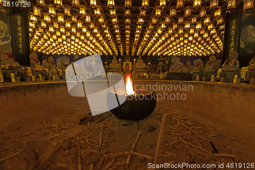 Image of Burning candle in Burner pot with and incense sticks in japanese cave temple.