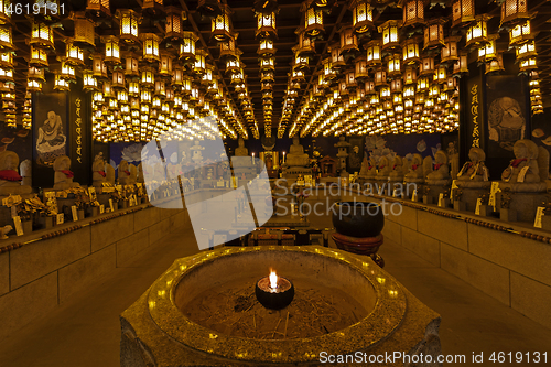 Image of Burner pot with burning candle and incense sticks in japanese cave temple.
