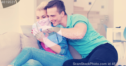 Image of couple relaxing at  home with tablet computers