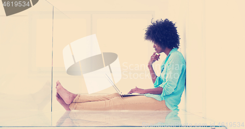 Image of black women using laptop computer on the floor