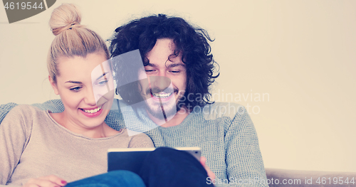 Image of couple relaxing at  home with tablet computers
