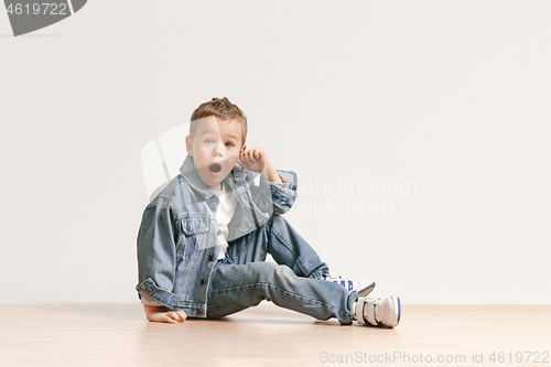 Image of The portrait of cute little boy in stylish jeans clothes looking at camera at studio