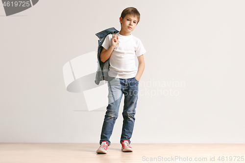 Image of The portrait of cute little boy in stylish jeans clothes looking at camera at studio