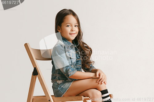 Image of The portrait of cute little kid in stylish jeans clothes looking at camera and smiling