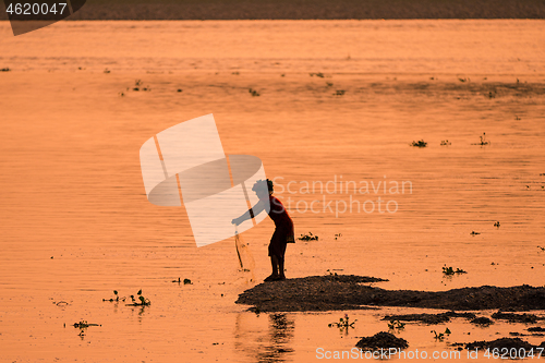 Image of Asian Woman fishing in the river, silhouette at sunset