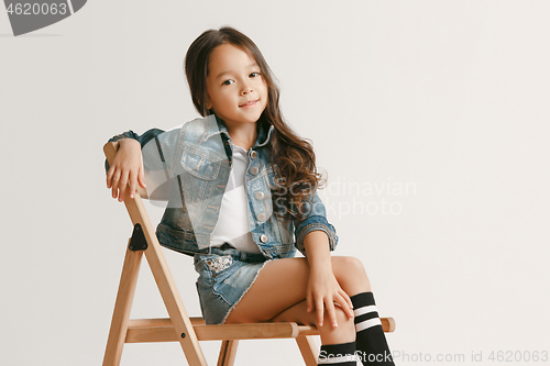 Image of The portrait of cute little kid in stylish jeans clothes looking at camera and smiling