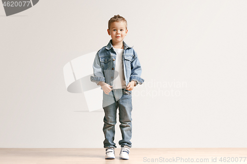 Image of The portrait of cute little boy in stylish jeans clothes looking at camera at studio
