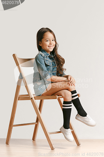Image of Full length portrait of cute little kid in stylish jeans clothes looking at camera and smiling