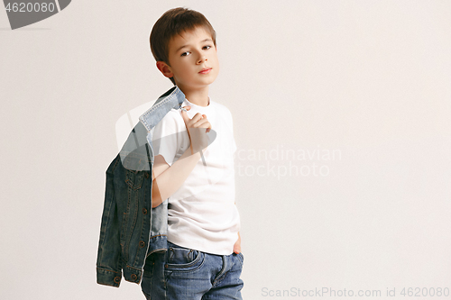 Image of The portrait of cute little boy in stylish jeans clothes looking at camera at studio