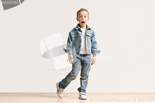 Image of The portrait of cute little boy in stylish jeans clothes looking at camera at studio