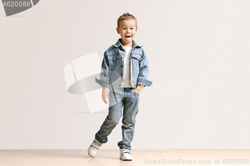 Image of The portrait of cute little boy in stylish jeans clothes looking at camera at studio