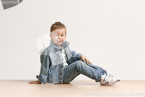 Image of The portrait of cute little boy in stylish jeans clothes looking at camera at studio