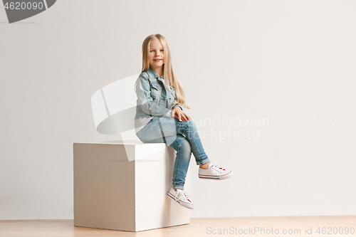 Image of The portrait of cute little kid in stylish jeans clothes looking at camera and smiling