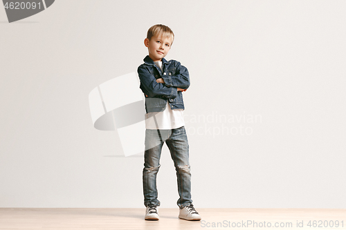 Image of The portrait of cute little boy in stylish jeans clothes looking at camera at studio