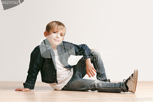 Image of The portrait of cute little boy in stylish jeans clothes looking at camera at studio