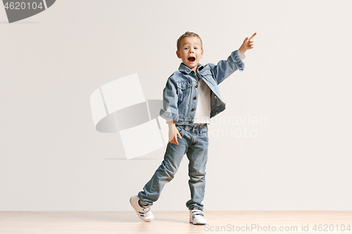 Image of The portrait of cute little boy in stylish jeans clothes looking at camera at studio