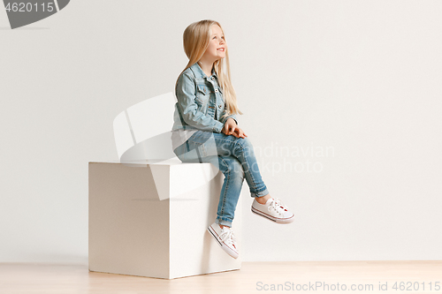Image of The portrait of cute little kid in stylish jeans clothes looking at camera and smiling