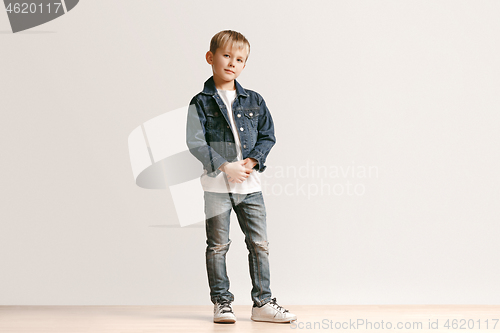 Image of The portrait of cute little boy in stylish jeans clothes looking at camera at studio