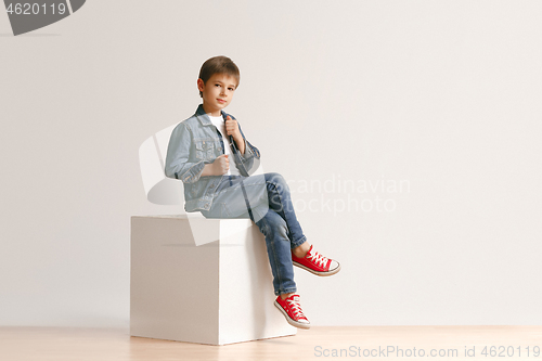 Image of The portrait of cute little boy in stylish jeans clothes looking at camera at studio